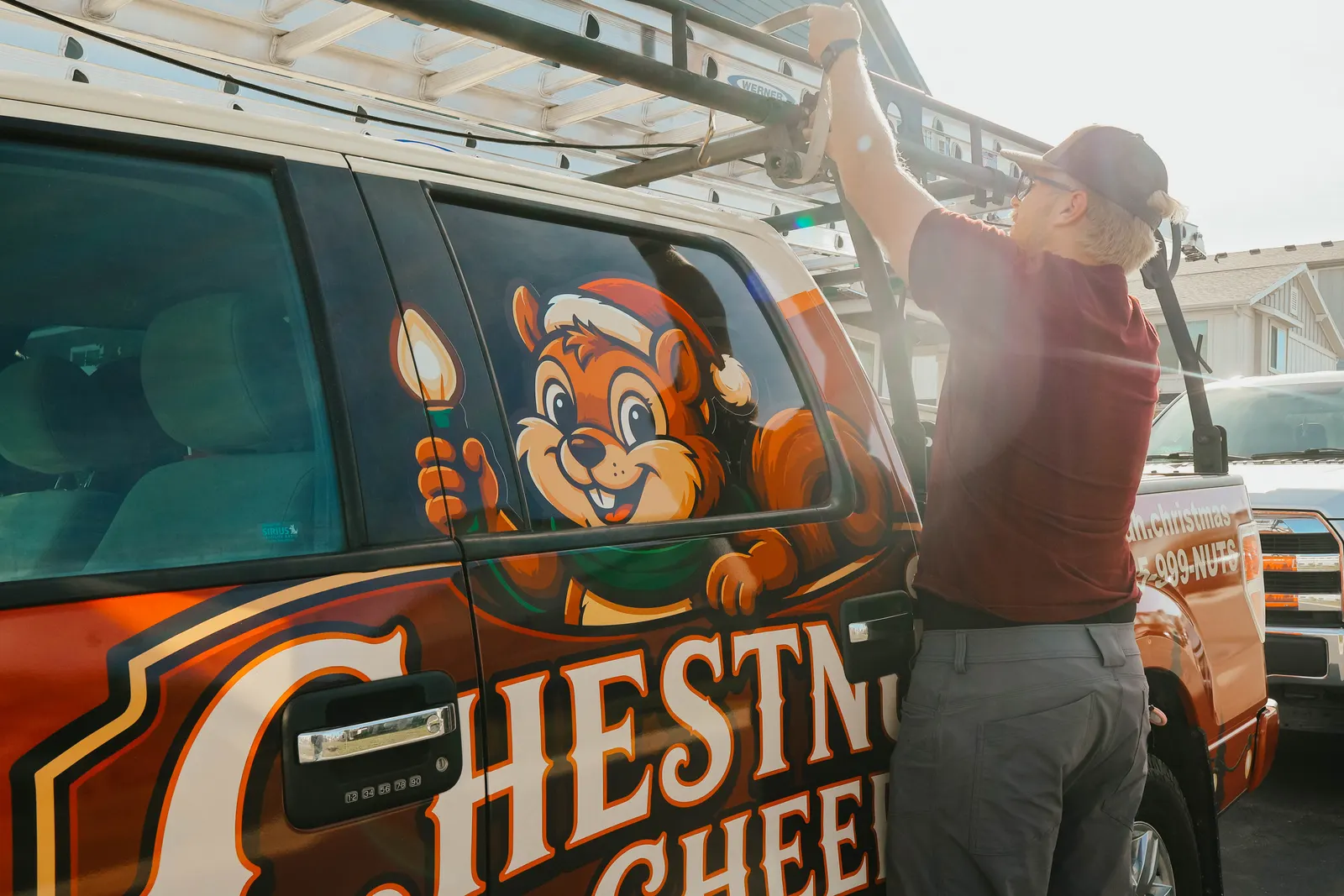 Chestnut & Cheer technician unloading a ladder from a branded Christmas lighting service truck