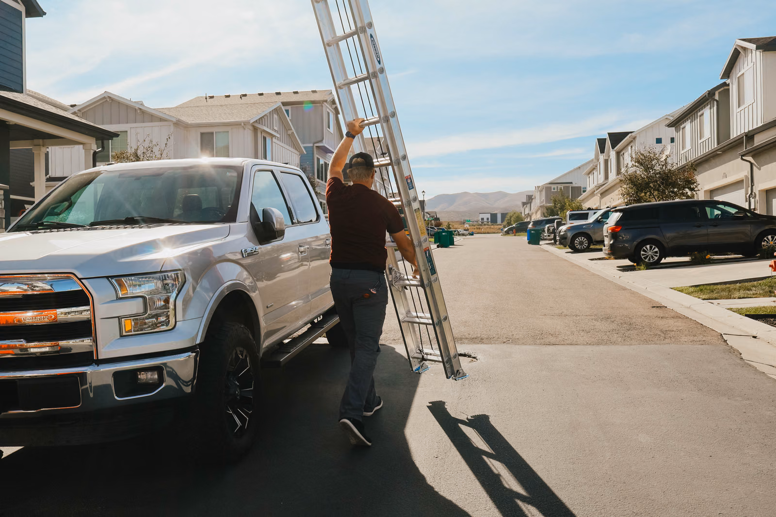 Chestnut & Cheer Christmas light technician carrying a ladder to a Utah installation